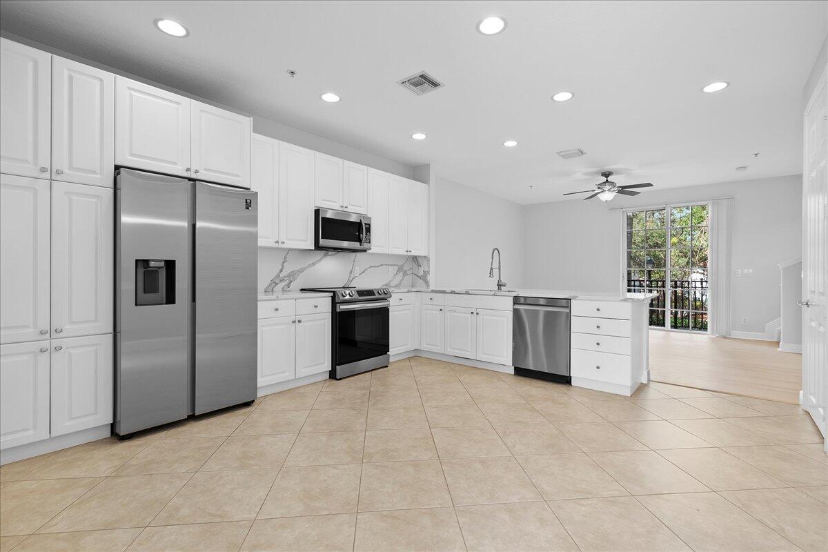 802 University Boulevard Jupiter, FL 33458 - Photo 12 of 40 a kitchen with white cabinets stainless steel appliances and a window
