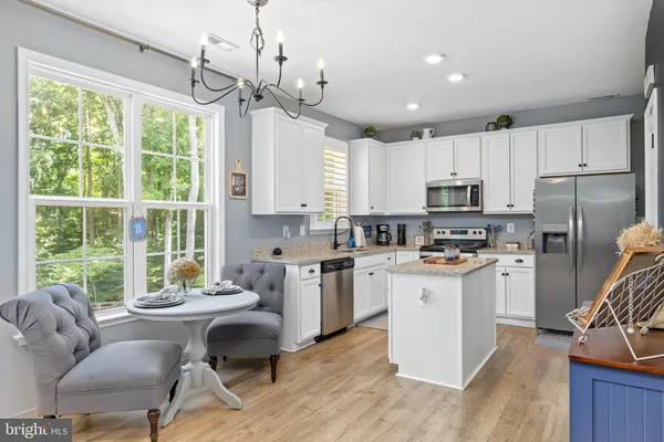 a kitchen with sink a stove a refrigerator cabinets dining table and chairs