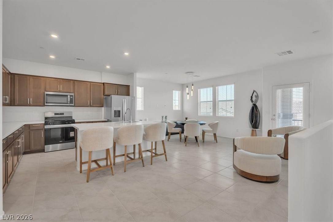 635 Bellus Place Henderson, NV 89015 - Photo 13 of 37 Kitchen featuring stainless steel appliances, a breakfast bar area, pendant lighting, a center island with sink, and light tile patterned floors