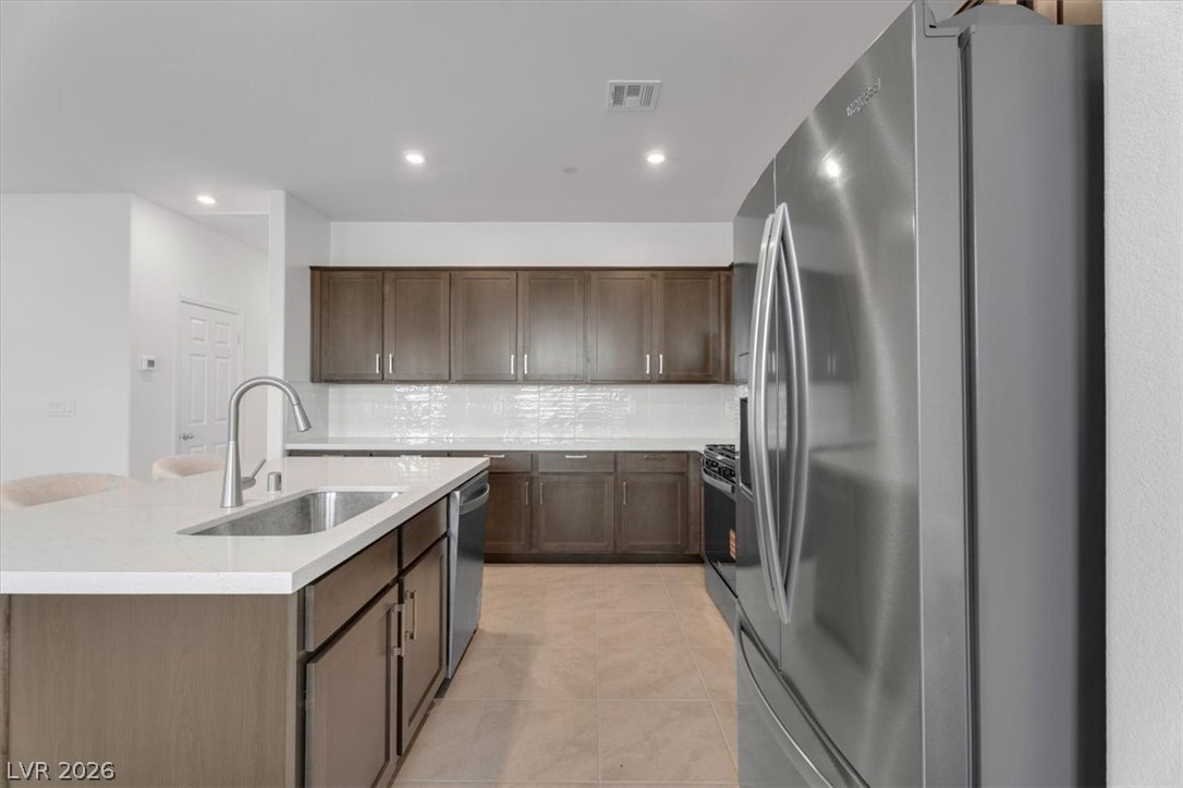 635 Bellus Place Henderson, NV 89015 - Photo 18 of 37 Kitchen with stainless steel appliances, recessed lighting, light stone countertops, a center island with sink, and decorative backsplash