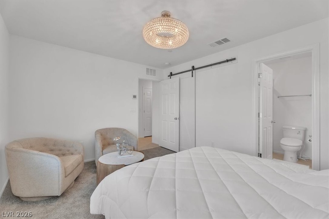 635 Bellus Place Henderson, NV 89015 - Photo 9 of 37 Bedroom with a barn door, light colored carpet, and ensuite bathroom