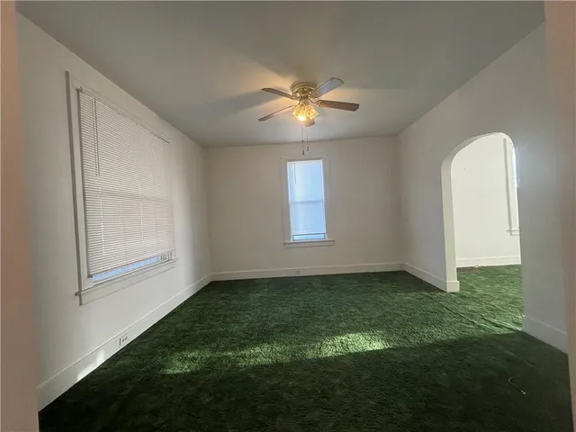 a view of an empty room with window and chandelier fan