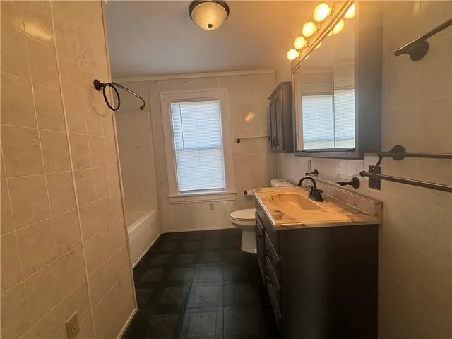a view of an empty room with window and chandelier fan