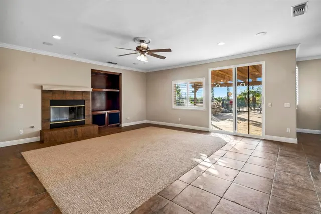 a view of a livingroom with a fireplace a ceiling fan and windows