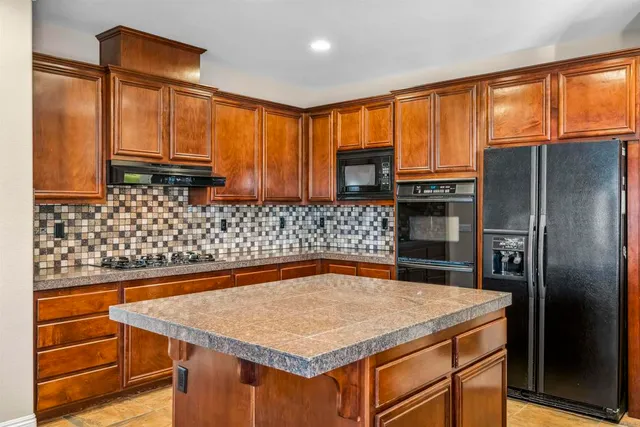 a kitchen with stainless steel appliances granite countertop a sink refrigerator and microwave