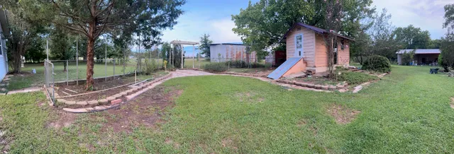 a view of a backyard with a slide trees and wooden fence