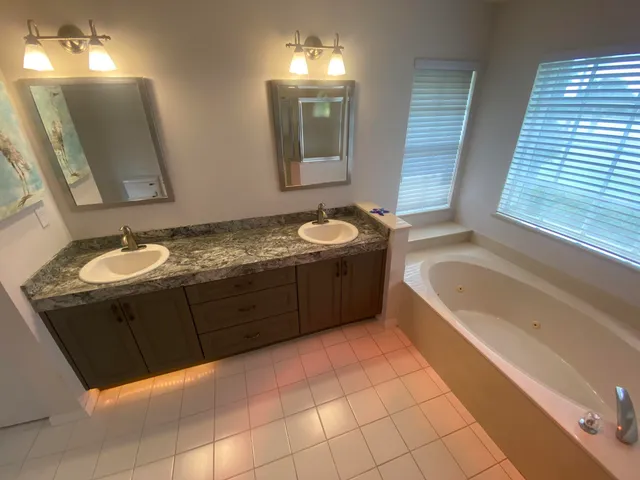 a bathroom with a granite countertop sink a mirror and bathtub