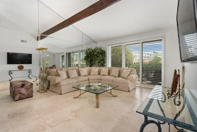 a living room with furniture a flat screen tv and a window