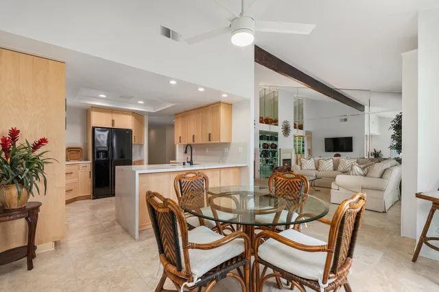 a dining room with furniture a potted plant and a kitchen view