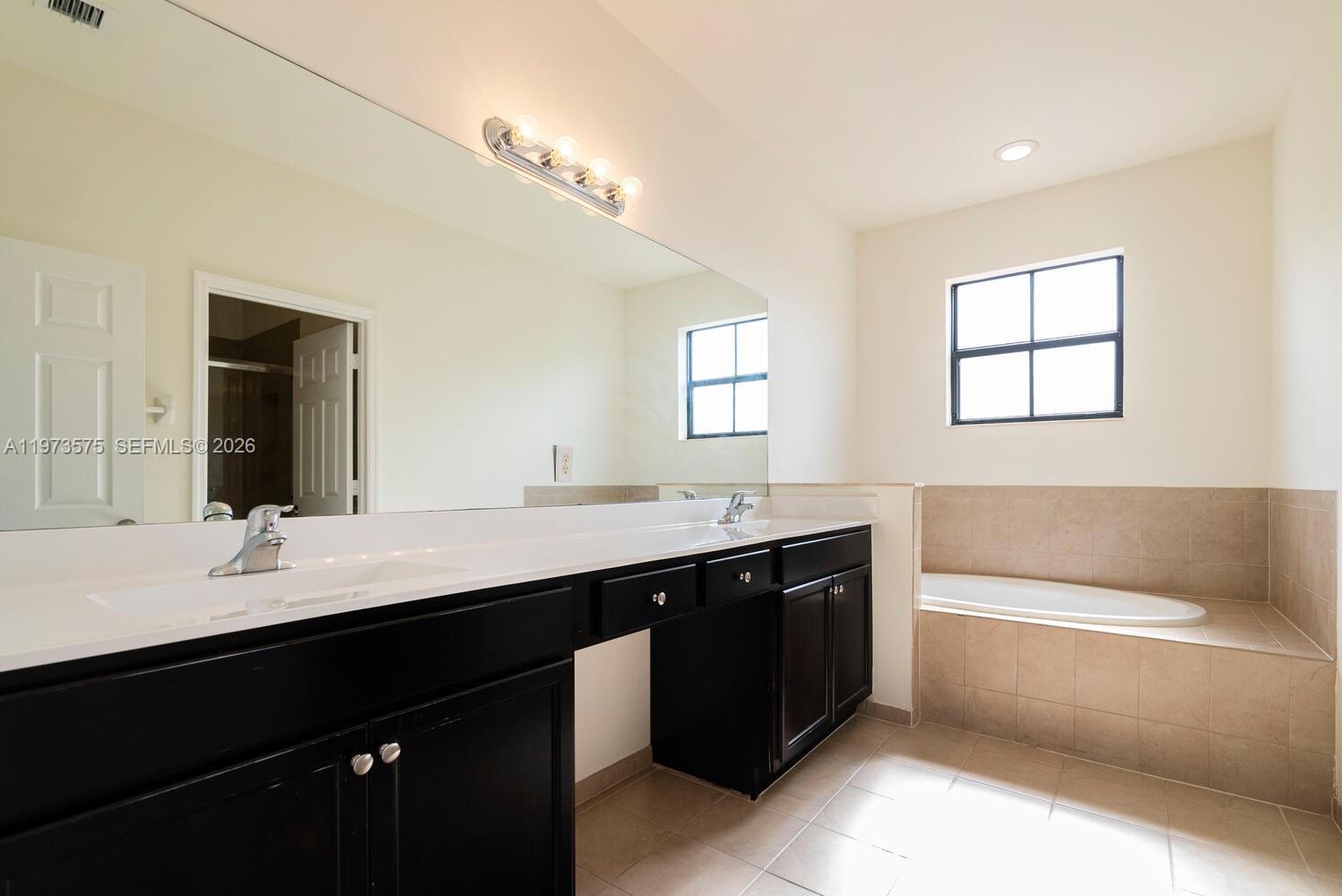 516 Southeast 35th Terrace Homestead, FL 33033 - Photo 13 of 25 a bathroom with a double vanity sink a tub and a mirror