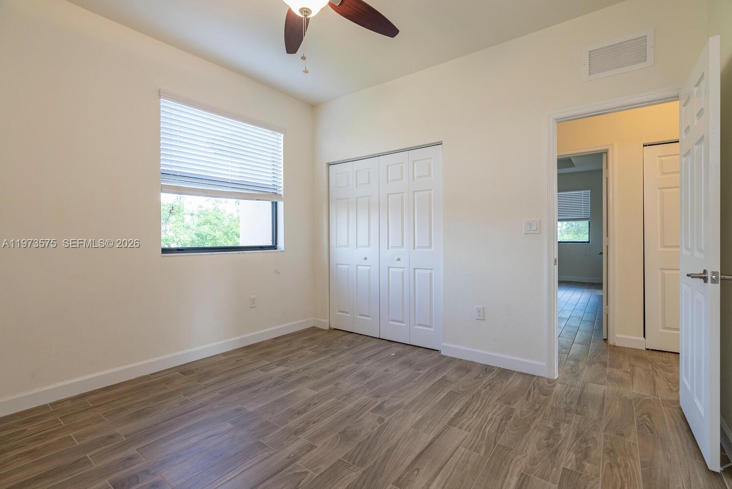 516 Southeast 35th Terrace Homestead, FL 33033 - Photo 16 of 25 an empty room with wooden floor chandelier fan and windows