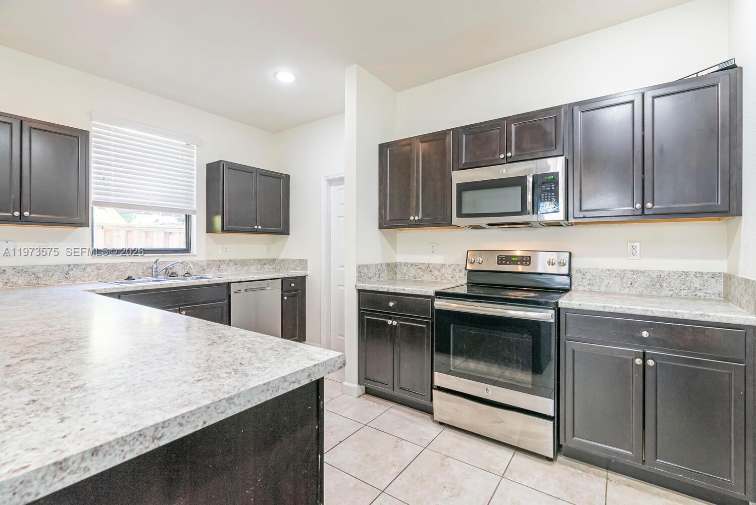 516 Southeast 35th Terrace Homestead, FL 33033 - Photo 2 of 25 a kitchen with stainless steel appliances granite countertop a stove microwave and sink