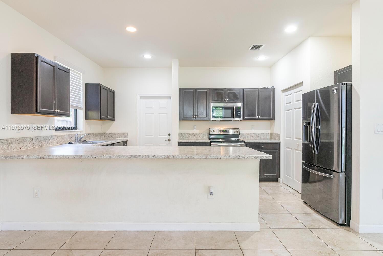 516 Southeast 35th Terrace Homestead, FL 33033 - Photo 3 of 25 a kitchen with stainless steel appliances granite countertop a refrigerator and a stove top oven