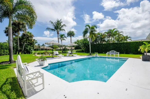 a view of a swimming pool and lounge chairs in back yard of the house