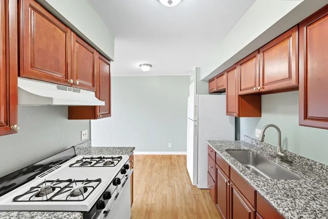 a kitchen with granite countertop a sink a refrigerator and cabinets