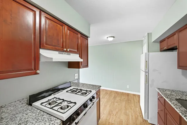 a kitchen with granite countertop a refrigerator and a stove top oven