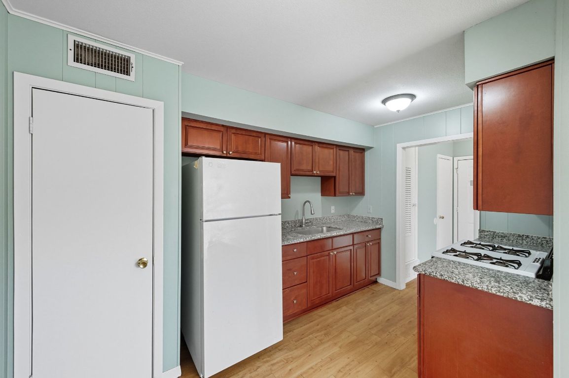 2208 Mission Hill Drive, Unit 103 Austin, TX 78741 - Photo 15 of 26 a kitchen with granite countertop a refrigerator and a stove top oven