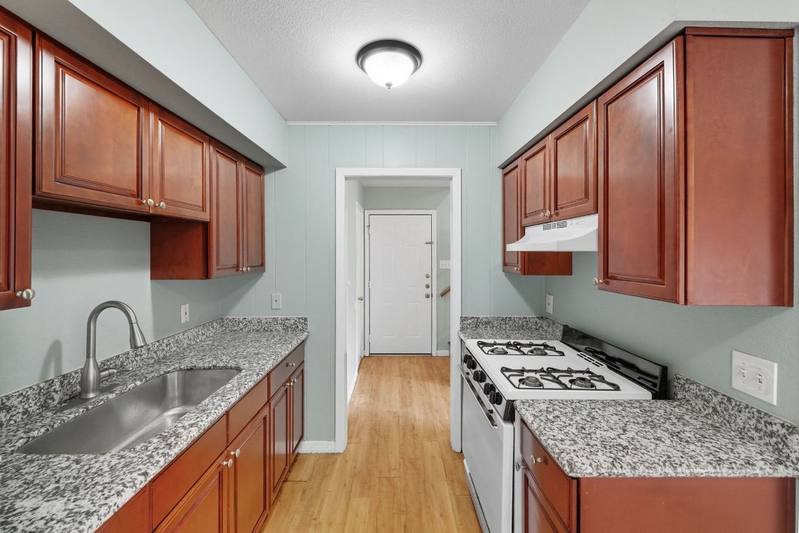 2208 Mission Hill Drive, Unit 103 Austin, TX 78741 - Photo 17 of 26 a kitchen with granite countertop a sink stove and cabinets