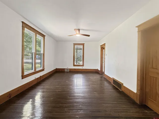 an empty room with wooden floor and windows