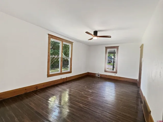 a view of an empty room with wooden floor and a window