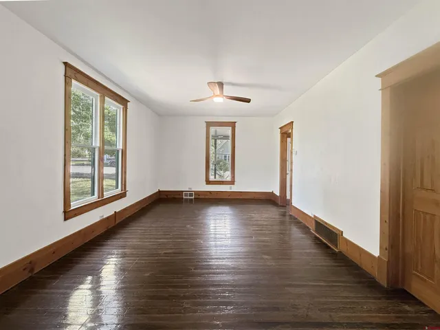 a view of an empty room with wooden floor and a window