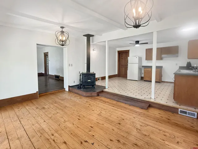 an empty room with wooden floor and chandelier