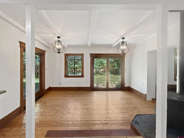 a view of an empty room with window and wooden floor
