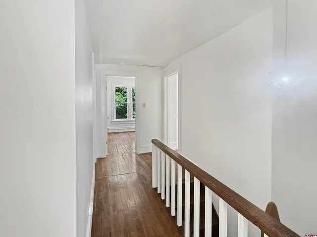 a view of a hallway with wooden floor and a window