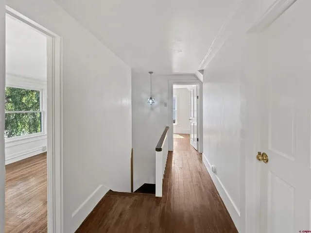 a view of a hallway with wooden floor and staircase