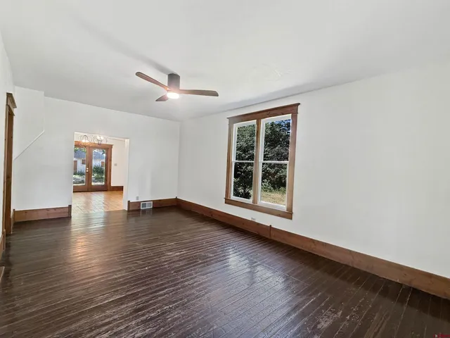 a view of an empty room with wooden floor and a window