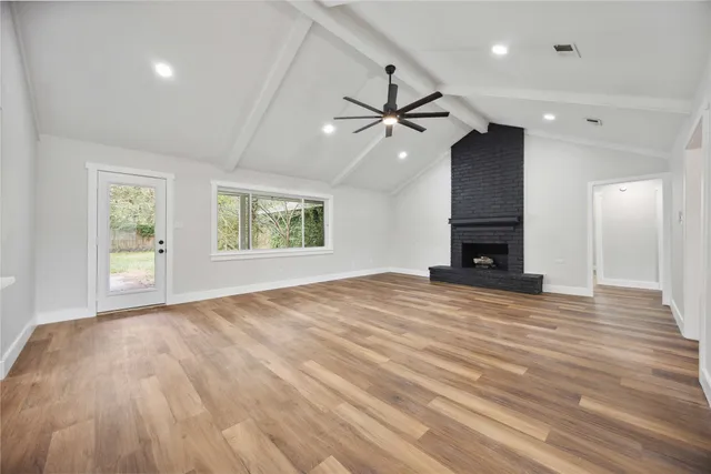 an empty room with wooden floor chandelier and windows