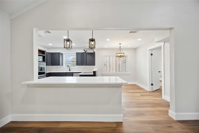 a view of a kitchen with kitchen island wooden floor and refrigerator
