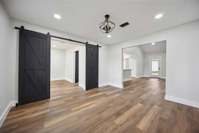 a view of an empty room with wooden floor and a ceiling fan