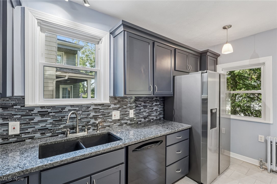 3621 Cedarbrook Road Cleveland, OH 44118 - Photo 6 of 40 Kitchen featuring black dishwasher, stainless steel fridge, light stone counters, backsplash, and decorative light fixtures