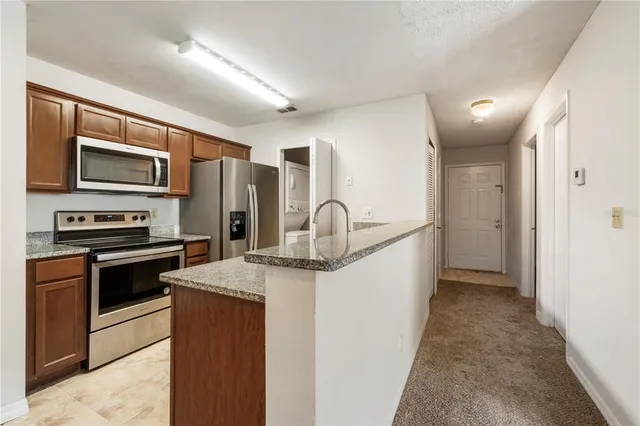 a kitchen with stainless steel appliances granite countertop a refrigerator a stove and a sink with wooden floor