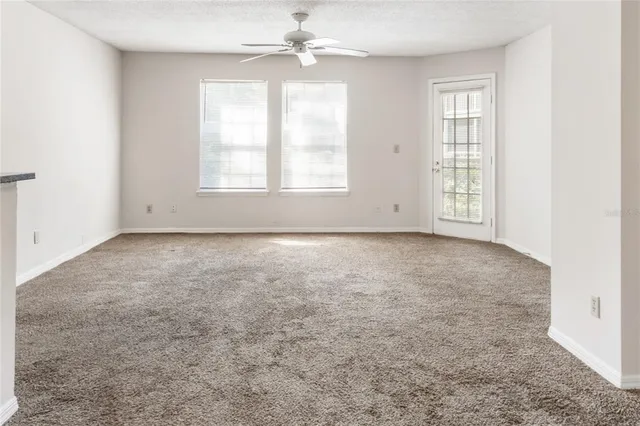an empty room with windows and chandelier fan