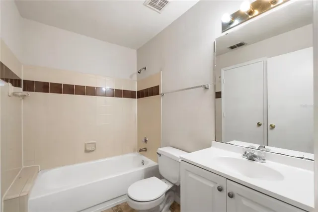 a bathroom with a bathtub shower sink vanity mirror and toilet