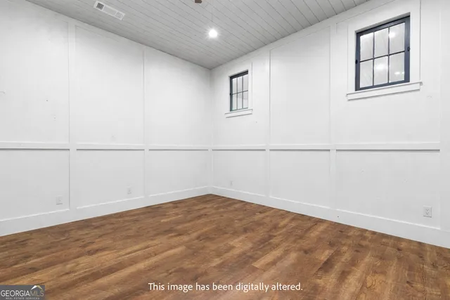 a view of an empty room with a window and wooden floor