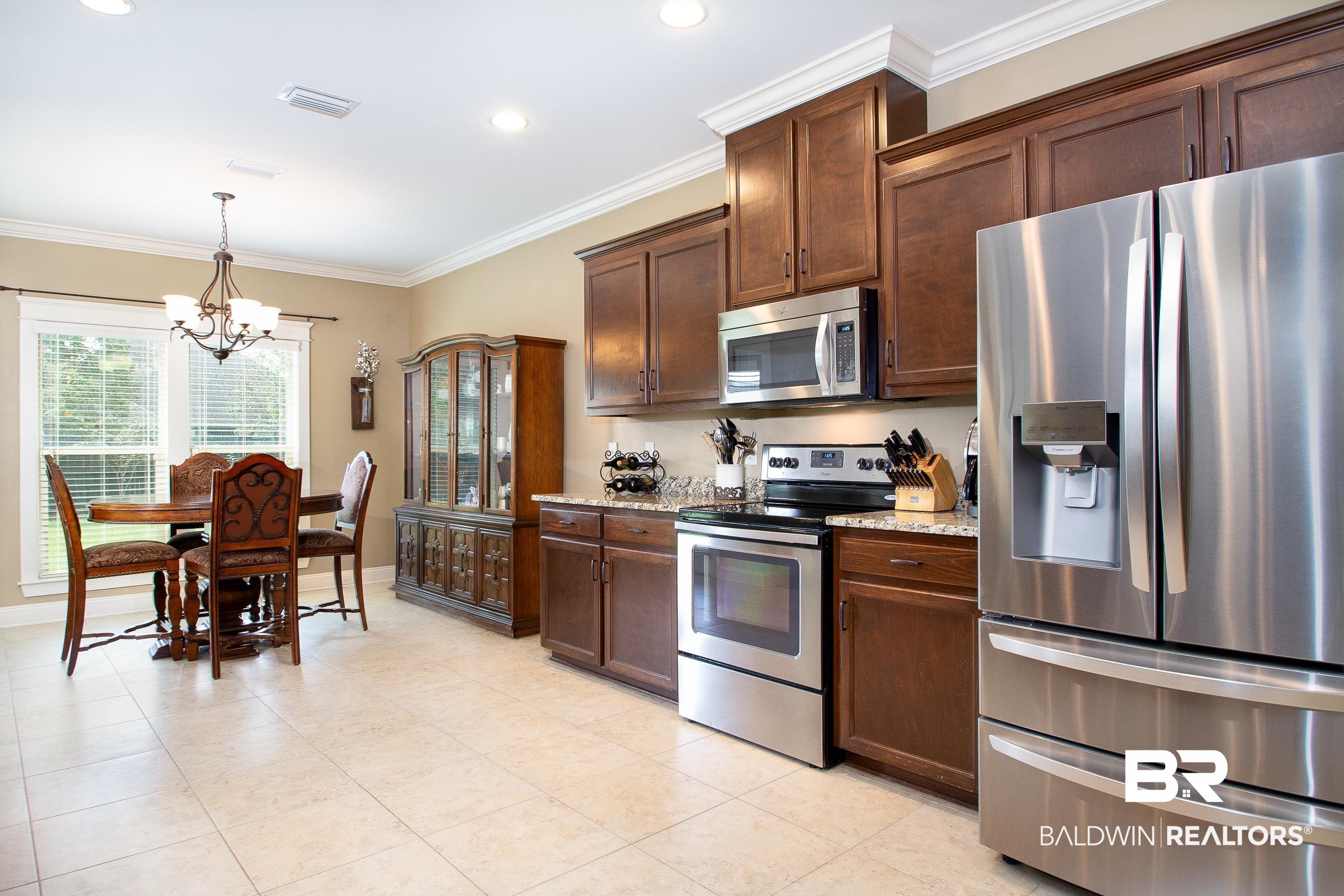 8625 Rosedown Lane Daphne, AL 36526 - Photo 10 of 29 Kitchen with light stone counters, ornamental molding, decorative light fixtures, stainless steel appliances, and a notable chandelier