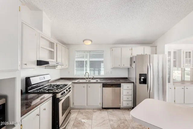 a kitchen with stainless steel appliances granite countertop a stove a refrigerator and a sink