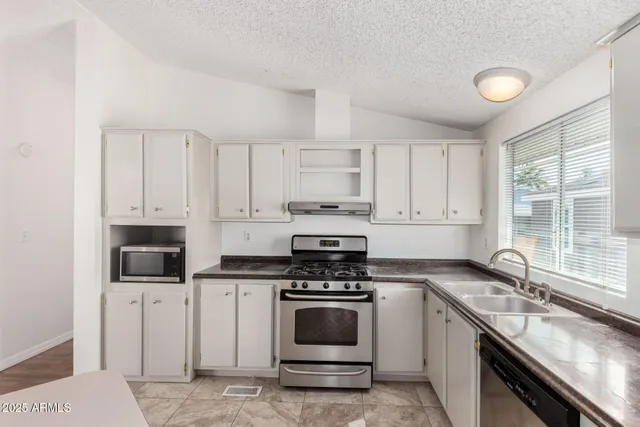 a kitchen with granite countertop a stove sink and cabinets