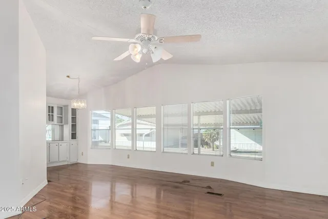 an empty room with wooden floor fan and windows