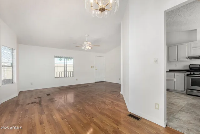 an empty room with windows and kitchen view