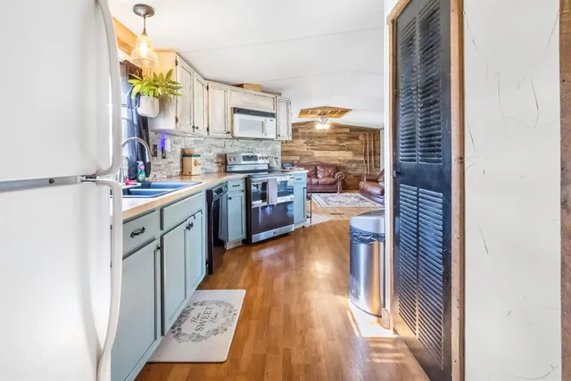 a kitchen with stainless steel appliances granite countertop a lot of counter top space and wooden floor