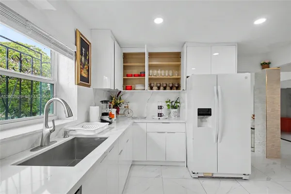 a kitchen with a refrigerator a sink and white cabinets
