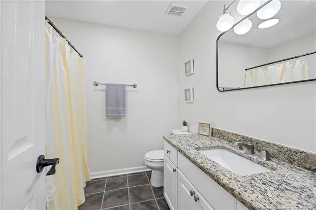 a bathroom with a granite countertop sink a toilet and a mirror