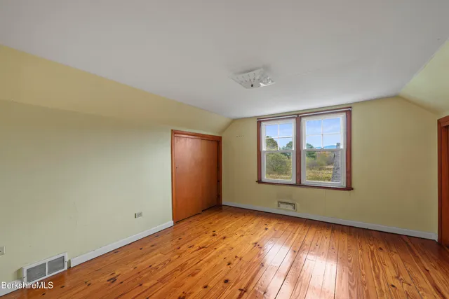 an empty room with wooden floor and closet area