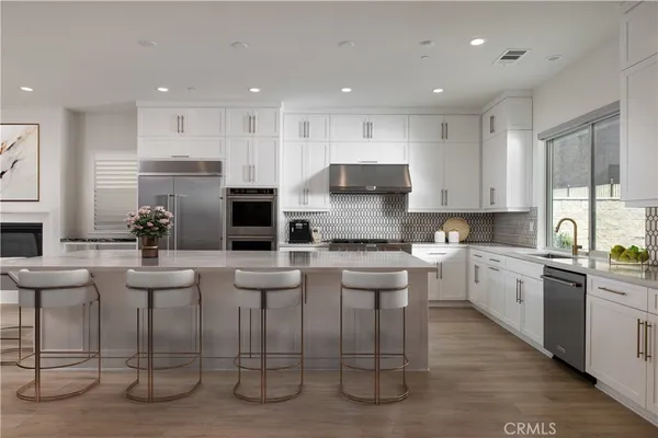 a kitchen with stainless steel appliances kitchen island granite countertop a stove top oven a sink and white cabinets