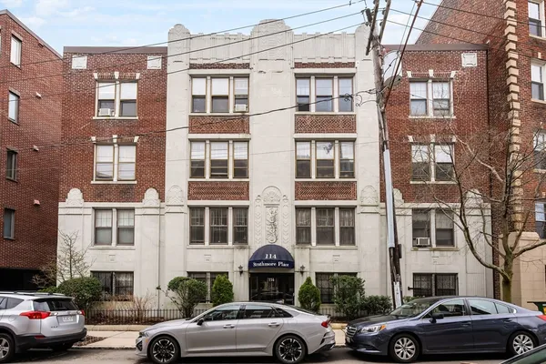 a front view of a building with cars parked