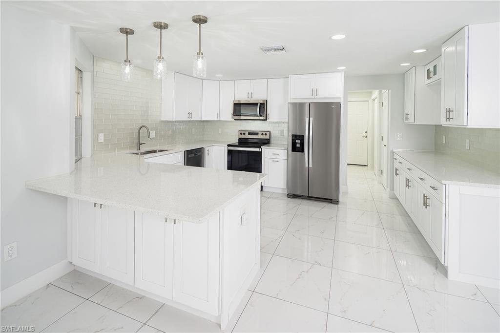 320 Bow Line Drive Naples, FL 34103 - Photo 11 of 20 a large kitchen with stainless steel appliances kitchen island granite countertop a refrigerator a stove a sink and white cabinets